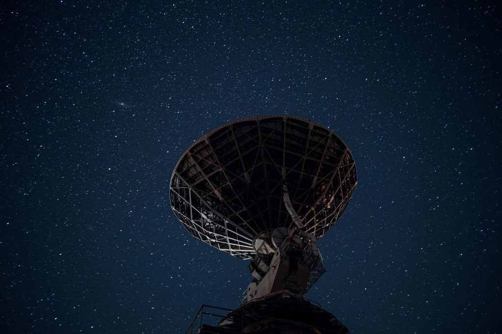 Silhouette of a satellite dish against a starry night sky, capturing cosmic exploration.